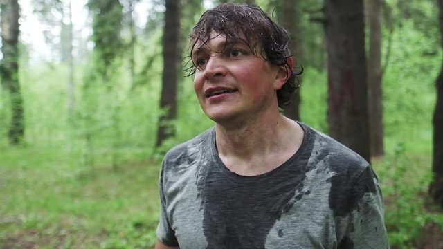 Portrait of the young man in wet t shirt standing in the forest