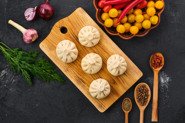 Top view of uncooked khinkali on wooden board with spice and herbs