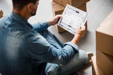 Young man studying plan of new dwelling