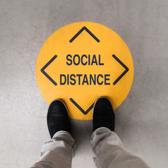 A person standing on a social distancing sign - 352584713