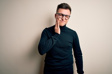 Young handsome caucasian man wearing glasses and casual sweater over isolated background touching mouth with hand with painful expression because of toothache or dental illness on teeth. Dentist