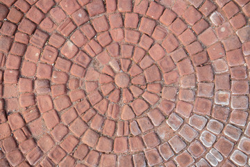 Old, red bricks arranged in a circle. Cobblestone. Texture, embossed background.