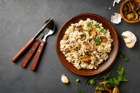Traditional italian cuisine meal - vegetarian risotto with mushrooms. Black stone backround.
