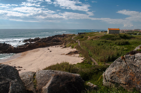 The old Stone Chapel on the hill above the ocean is covered with green grass. Below the white sand beach