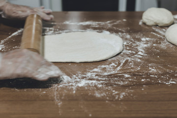 Hands of a woman making dough with plastic gloves on the table