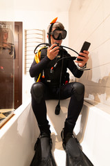 A man learns through online lessons with his smartphone to dive, in the bathtub of his house. Home...