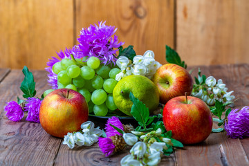 apples, lemon, grapes and flowers on a wooden background