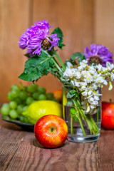 apples, lemon, grapes and flowers on a wooden background