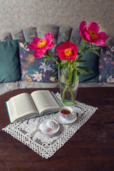 Vase of peony flowers with book tea and zephyr