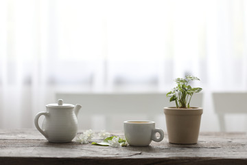 Fototapeta na wymiar White tea cup and tea pot with plant on wooden table minimal interior 