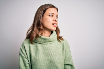 Fototapeta premium Young beautiful blonde girl wearing winter sweater standing over isolated background looking away to side with smile on face, natural expression. Laughing confident.