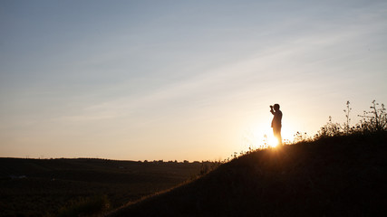 Senior man looking at the horizon in the field on top of a hill in backlight.