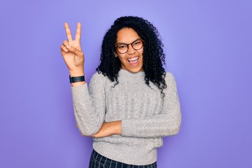 Young african american woman wearing casual sweater and glasses over purple background smiling with...