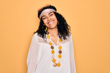 Young african american curly hippie woman wearing sunglasses and vintage accessories winking...
