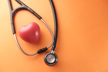heart shape symbol and stethoscope on orange background 
