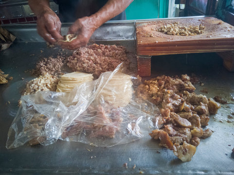 Elaboraci&oacute;n de tacos tradicionales de diversos tipos de carnita, como barbacoa, oreja, sesos entre otros, se alcanza a ver las carnitas, la tabla de cortar carne y las manos de el taquero o cocinero.