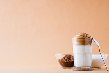 cold dalgon coffee in clear glasses on a dark wooden background. foam from sugar and instant coffee is whipped with a mixer over cold milk. Indian national whipped coffee. coffee beans.