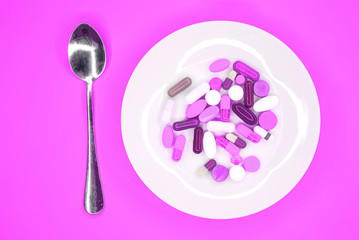 white plate with pills and spoon on turquoise background