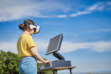 girl with a computer and virtual reality glasses on the mountain