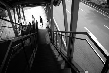 Silhouette of woman walking away down the stairs, black and white. Loneliness, depression or anxiety concept