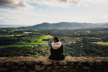 mujer mirando de espaldas desde un castillo al atardecer en los campos españoles con un cielo...