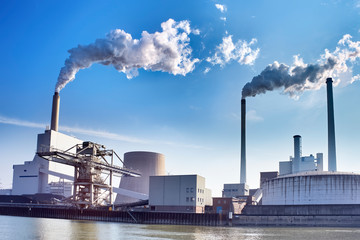 Power plant with chimneys and smoke at the riverbank