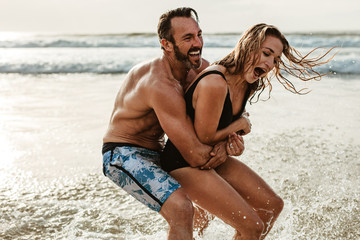 Playful couple having fun on their summer beach vacation