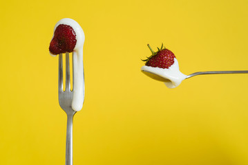 Macro shot of ripe strawberries on a fork with sour cream. Closeup red berry on a spoon. Yellow background - 352600117