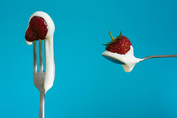 Macro shot of ripe strawberries on a fork with sour cream. Closeup red berry on a spoon. Blue background - 352600164