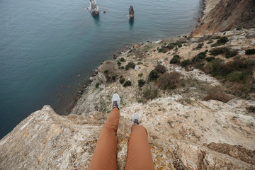 A man sits on the edge of a cliff, lowered his legs down. Aerial view of the Black sea - 352600942