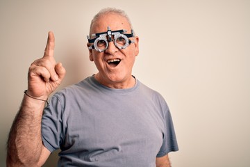 Middle age hoary man controlling vision wearing optometry glasses over white background pointing finger up with successful idea. Exited and happy. Number one.