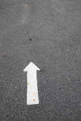 White arrow on cracked asphalt surface. Concept traffic.