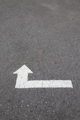 White arrow on cracked asphalt surface. Concept traffic.