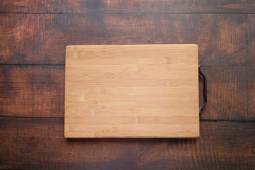 Top view of wooden chopping board on gray background .