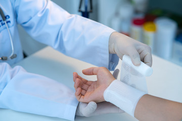The medical doctor is wrapping the cloth for the patient.