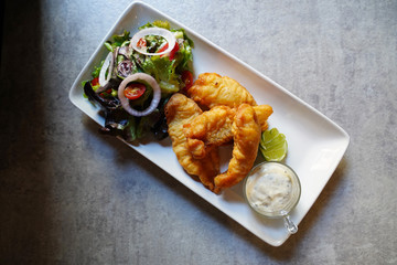 Crispy fired fish with sour cream, salad and lemon on white plate, top view of Crispy fired fish