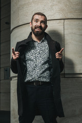 Happy bearded businessman after successful deal playing the fool outside his office building.