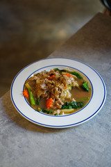 Fried noodles with pork and kale in gravy sauce on white plate