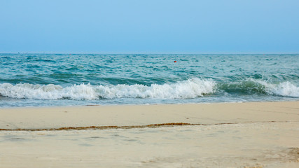 A foamy sea wave runs onto the yellow coastal sand in the evening.