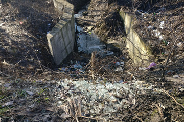 Garbage is lying in the drainage channel. Trash in the city riverbed