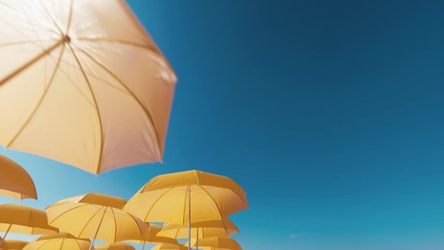 Beach umbrellas against blue sky. Yellow beach umbrellas on a background of blue sky