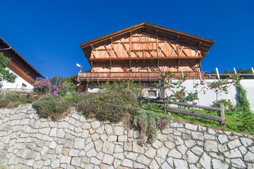 typical mountain building in stone, white plaster and wood and with colorful flowers