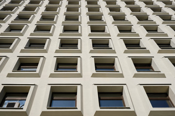 Identical square windows of a concrete building with air conditioning going up