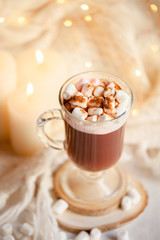 Winter hot drink: hot chocolate with marshmallow. Delicious sweet beverage. Christmas lights on background. Cozy home atmosphere, holiday festive mood. Close up, macro