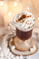 Winter hot drink: hot chocolate with marshmallow and whipped cream. Delicious sweet beverage. Christmas lights on background. Cozy home atmosphere, holiday festive mood. Close up, macro