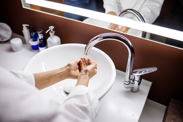 Female washing hands in sink indoors in evening