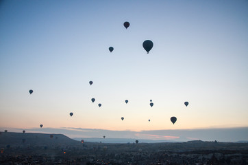 Hot air balloons at sunrise flying in the sky along valleys at Cappadocia of Goreme, Turkey 