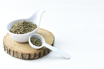 Chopped dried leaves of basil leaves on white wooden background