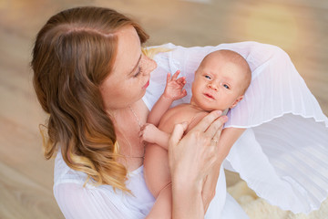 Blonde Mom holds her 2-month-old baby in her arms and smiles