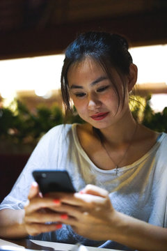 Beautiful Cute Happy Smiling Asian Chinese Girl Using Phone At The Restaurant, Ordering Food Online, Gadget Addiction, No Talking With Friends, Life Online Concept